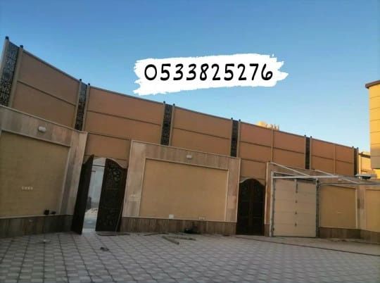 ساتر بيج مرتفع فوق سور منزل وبوابات حديد مزخرفة، منظر من الشارع